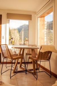 mesa y sillas en una habitación con ventana en Duplex a estrenar a pocos metros del gutierrez en San Carlos de Bariloche
