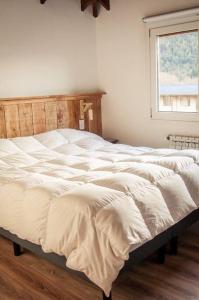 1 cama blanca grande en un dormitorio con ventana en Duplex a estrenar a pocos metros del gutierrez en San Carlos de Bariloche