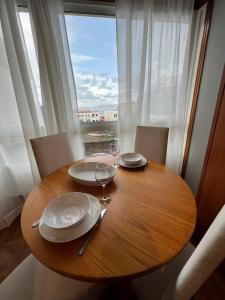 une table en bois avec des assiettes et des verres à vin ainsi qu'une fenêtre dans l'établissement Valterra Vigo, à Vigo