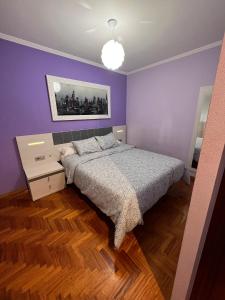 - une chambre avec un lit et un mur violet dans l'établissement Valterra Vigo, à Vigo