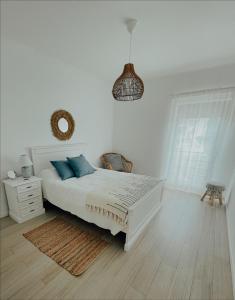 a white bedroom with a bed with blue pillows at Monte Azul Penthouse in Ribeira Grande