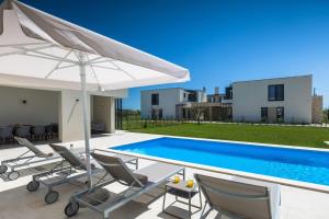 a villa with a swimming pool with chairs and an umbrella at Villa Bella and Chiara by SeeAdria Agency in Brtonigla