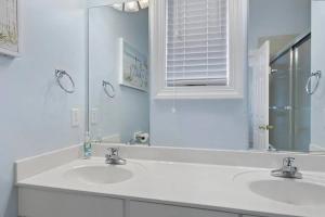 a white bathroom with two sinks and a mirror at Paradise Villa in Ocean Isle Beach +18 photos
