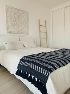 a bed with a blue and white striped blanket on it at Monte Azul Penthouse in Ribeira Grande