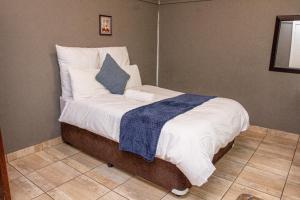 ein Bett mit weißer Bettwäsche und einem blauen Kissen darauf in der Unterkunft BLUEBERRY BED AND BREAKFAST in Pietermaritzburg
