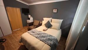 a small bedroom with a bed and a chair at BLUEBERRY BED AND BREAKFAST in Pietermaritzburg