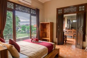 a bedroom with a bed and a large window at Purnama House in Ubud