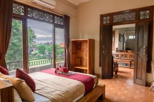 een slaapkamer met een bed en een groot raam bij Purnama House in Ubud