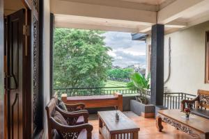 a room with a balcony with a table and chairs at Purnama House in Ubud