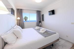 een slaapkamer met een wit bed en uitzicht op de oceaan bij Fantastic Ocean view apartment Buena Vista with amazing Pools in Acantilado de los Gigantes