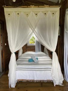a bedroom with a bed with a canopy and a window at Bungalow à flanc de colline in Le Morne Rouge