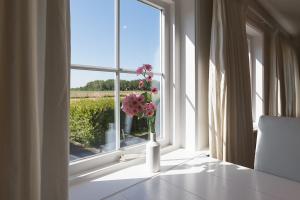 eine Vase mit rosa Blumen im Fenster in der Unterkunft Hello Zeeland - Vakantiehuis Brouwerijweg 43-3 in Domburg