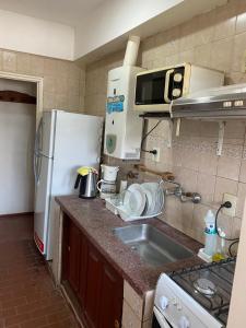 uma cozinha com um lavatório e um frigorífico branco em Departamento completo a dos cuadras de la plaza principal , sin ascensor por el momento y con cochera em San Ramón de la Nueva Orán