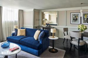 uma sala de estar com um sofá azul e uma mesa em The Royal Horseguards Hotel, London em Londres