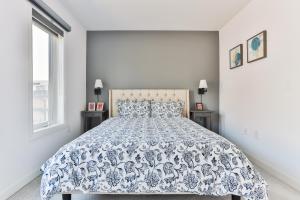 a bedroom with a bed with a blue and white bedspread at 3bdr townhouse in Downsview Park - Free parking - 25 min to Downtown in Toronto
