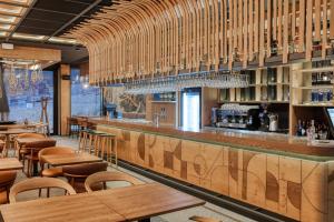 a restaurant with a bar with wooden tables and chairs at Galeria Jahorina Luxury Ski Apartments and Restaurant in Jahorina