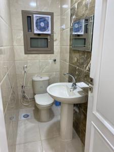 a bathroom with a toilet and a sink at شقة فندقية مميزة بالمنصورة in Ṭalkha