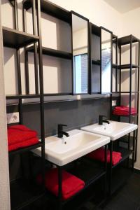 a bathroom with two sinks with mirrors and red towels at Ferienwohnungen Brombachsee in Pleinfeld