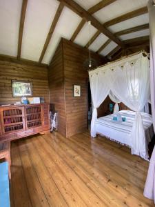 a bedroom with a canopy bed and a wooden floor at Bungalow à flanc de montagne in Le Morne Rouge