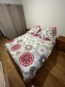 a bed with a flowered blanket and pillows on it at 4 pièces avec parking à 2 min du centre commercial et du lac de Créteil in Créteil