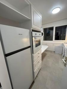 a white kitchen with a refrigerator and a stove at 4 pièces avec parking à 2 min du centre commercial et du lac de Créteil in Créteil