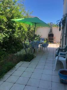 un patio con una mesa y una sombrilla verde en Les Micocouliers - Spacieuse maison,4chambres ,avec Jardin- Parking -Wifi en Béziers