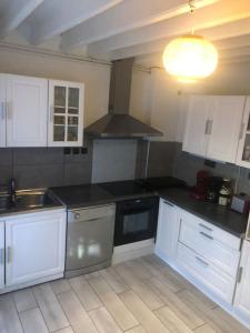 una cocina con armarios blancos y encimeras negras en Les Micocouliers - Spacieuse maison,4chambres ,avec Jardin- Parking -Wifi en Béziers