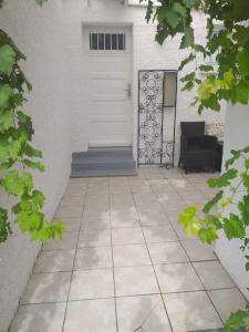 un patio con una puerta blanca y una silla negra en Les Micocouliers - Spacieuse maison,4chambres ,avec Jardin- Parking -Wifi en Béziers