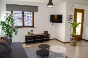 ein Wohnzimmer mit einem Sofa, Tischen und einem TV in der Unterkunft BBkey La casetta Arta Terme in Arta Terme