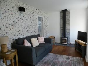 sala de estar con sofá y chimenea en Delfryn Holiday Cottage en Colwyn Bay