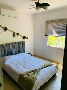 um quarto com uma cama, uma ventoinha e uma janela em La Casa de Leo Recamara 1 Villa Cardiell QROO em Playa del Carmen