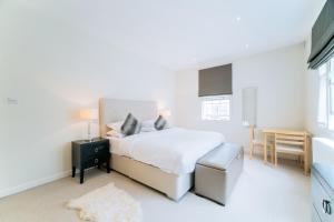 Dormitorio blanco con cama y mesa en Clarges - Grand Park Street Apartments, en Londres