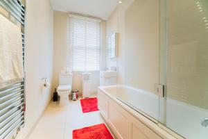y baño blanco con bañera y ducha. en Clarges - Grand Park Street Apartments, en Londres