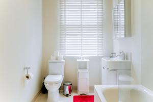 Baño blanco con aseo y lavamanos en Clarges - Grand Park Street Apartments, en Londres