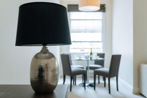 una lámpara sobre una mesa con sillas en Clarges - Grand Park Street Apartments, en Londres