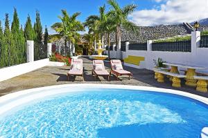 um quintal com uma piscina, cadeiras e uma mesa em Villa Don Pedro em Tijarafe