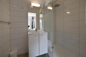 La salle de bains blanche est pourvue d'un lavabo et d'un miroir. dans l'établissement L'Aiglon Bylitis, à Porto-Vecchio