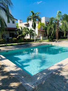 una piscina con palmeras y un edificio en La Casa de Leo Recamara 1 Villa Cardiell QROO, en Playa del Carmen