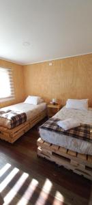 2 bedden in een slaapkamer met houten vloeren en een raam bij Cabañas Sierra Dorotea in Puerto Natales