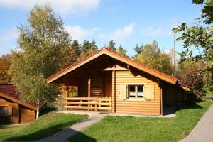 Cabaña de madera con porche y árbol en Naturerlebnisdorf Stamsried 3, en Stamsried