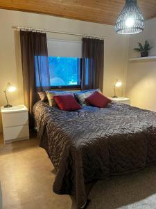 1 dormitorio con 1 cama grande y 2 almohadas rojas en Tilava huoneisto, en Saarijärvi