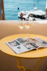 un tavolo con due bicchieri da vino e una rivista di Anelia House a Oia