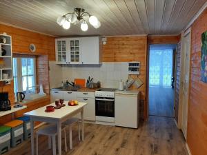 una cocina con electrodomésticos blancos y una mesa con sillas. en Otsa puhkemaja, en Raudsepa