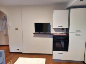 eine Küche mit weißen Schränken und einem TV an der Wand in der Unterkunft Appartamento Sophie LT in Santa Maria Maggiore