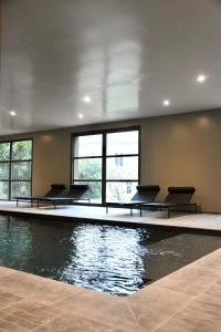 a swimming pool with benches in a room with water at Domaine de La Soudelle in Chanceaux-sur-Choisille