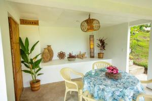 ein Esszimmer mit einem Tisch mit Stühlen und Vasen in der Unterkunft Kingfisher Garden Homestay 2 in Guindulman