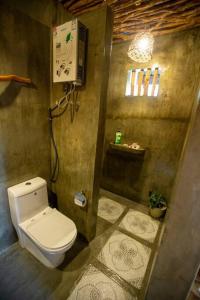 a bathroom with a white toilet in a room at Kingfisher Garden Homestay 2 in Guindulman