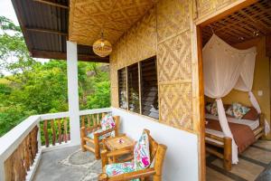 a porch of a house with a bed and chairs at Kingfisher Garden Homestay 2 in Guindulman