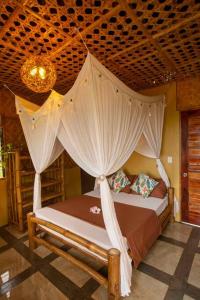 a bedroom with a canopy bed with curtains and a chandelier at Kingfisher Garden Homestay 2 in Guindulman