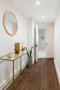 a hallway with a table and a mirror at Luxury Chelsea Flat in London